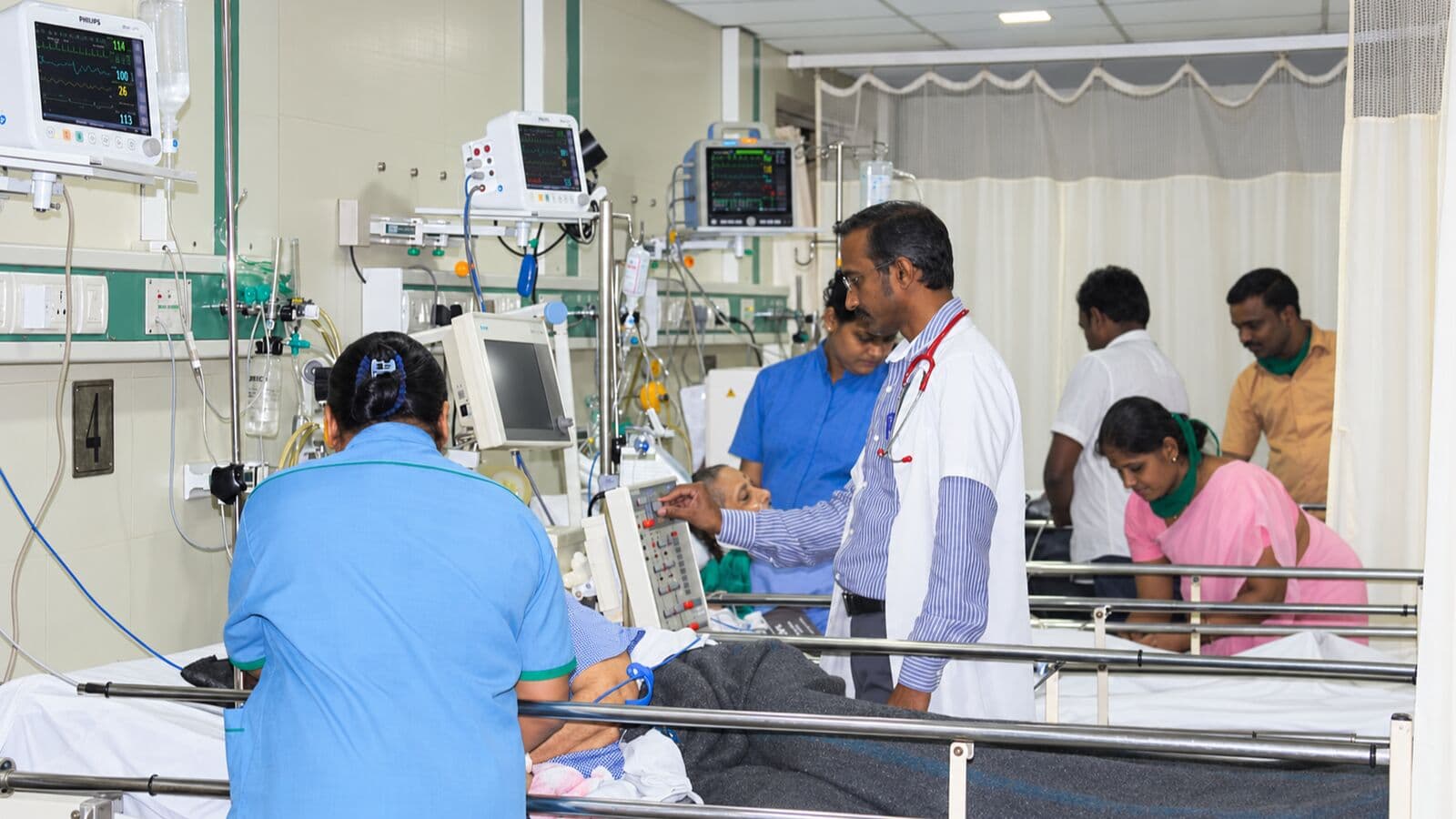 A THC doctor checking a patient's monitor at the bedside in the ICU